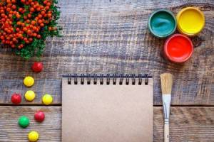56757942-hobby-painting-workplace-with-colored-pencils-gouache-jars-dragee-open-blank-notebook-on-wooden-tab